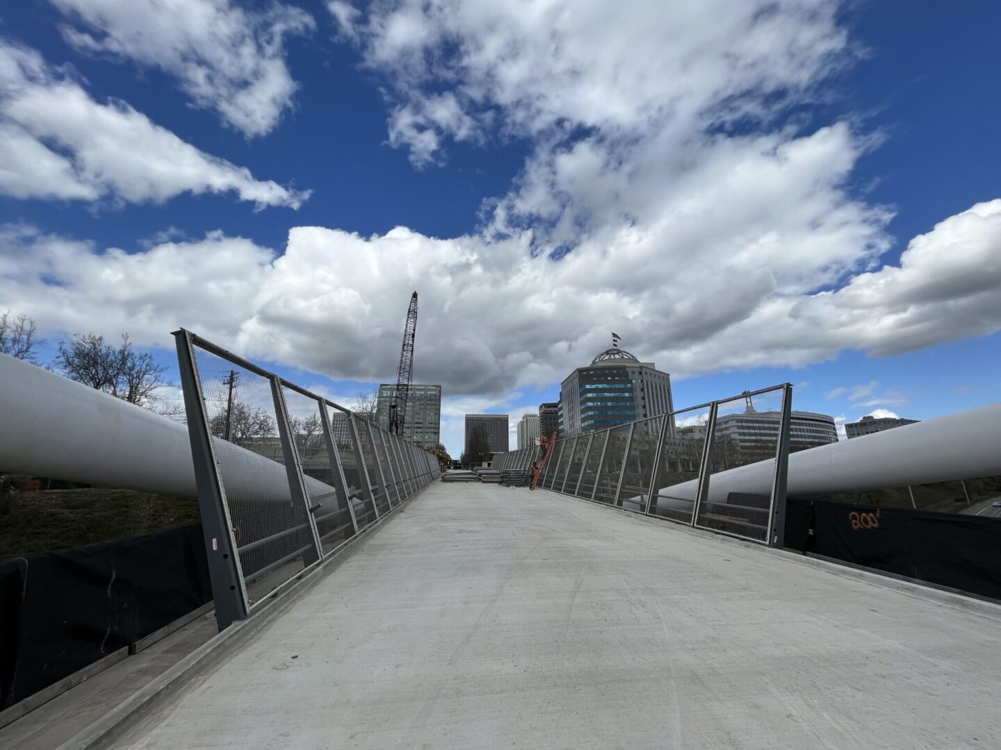 A bridge with some pipes on it and clouds in the sky